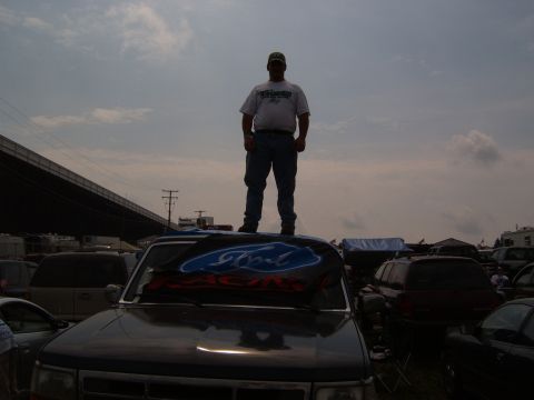 1993 Ford Bronco - A Ford Racing banner is displayed on the hood of a dark SUV in a junkyard.