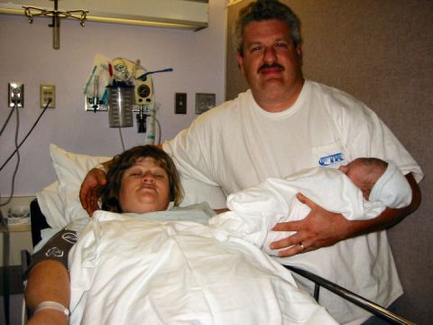1972 Ford Ranchero - A proud father holds his newborn baby while the mother rests in a hospital bed.