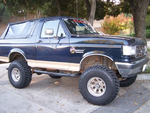 1991 Ford Bronco - This lifted Ford Bronco has a dark blue exterior with tan trim and aggressive off-road tires.