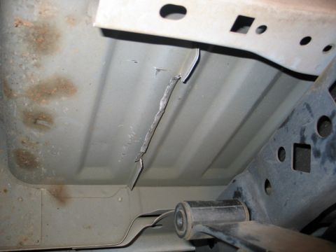 2004 Ford F-150 - Underside view of a 2004 Ford F-150 frame showing damage to a metal strip.