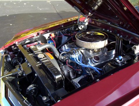 1969 Ford Mustang - The engine bay of a classic car, a V8 engine with a chrome air cleaner and red paint.