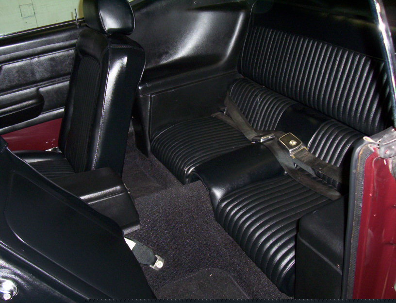 Black vinyl rear seat and interior of a 1969 Ford Mustang with seat belts and black carpet