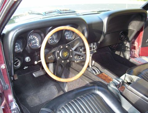 1969 Ford Mustang - The interior of a 1969 Ford Mustang features a wood-rimmed steering wheel, black upholstery, and a classic dashboard layout.