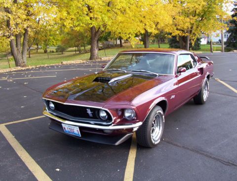 1969 Ford Mustang - Burgundy 1969 Ford Mustang parked in a lot with fall foliage in the background.