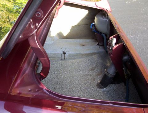 1969 Ford Mustang - The interior of a car's trunk is shown, revealing the spare tire well and carpeting.