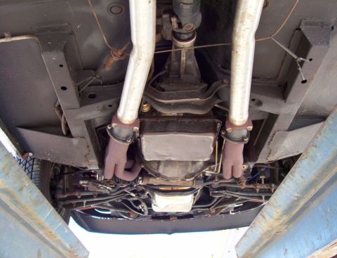1969 Ford Mustang - The undercarriage of a 1969 Ford Mustang is visible, with a focus on the exhaust system and drivetrain components.