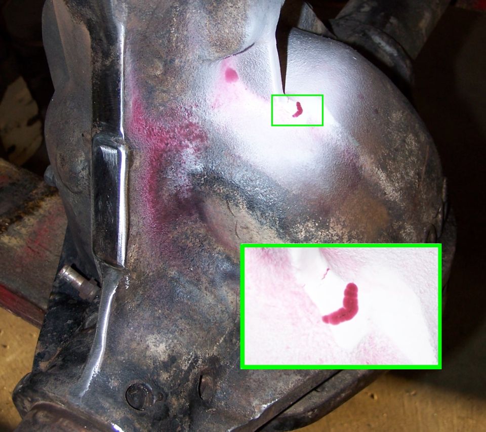 close-up of a metal part with red dye showing cracks, with a magnified inset
