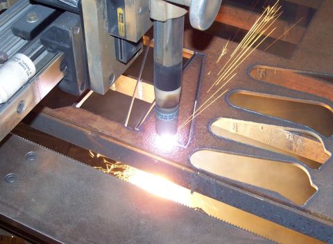 1979 Ford Bronco - A plasma cutter is actively cutting intricate shapes into a piece of metal, generating a shower of sparks.