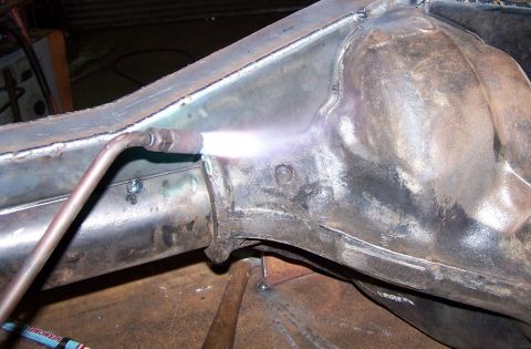 1979 Ford Bronco - Metal frame component being welded with a torch.