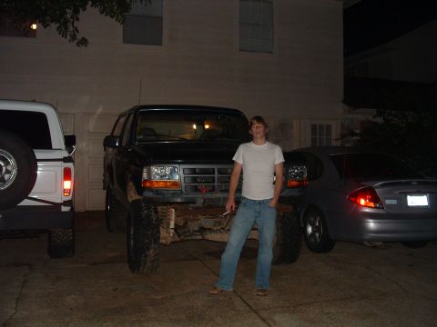 1993 Ford Bronco - A young man poses with a lifted black Ford Bronco parked in a driveway at night.