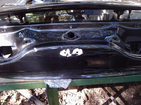 2000 Ford Taurus - A black car trunk lid is shown with damage and primer applied to repair it.