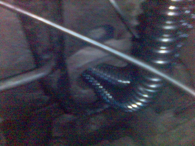 Close-up of a coiled suspension spring and a metal rod, likely from a vehicle's undercarriage