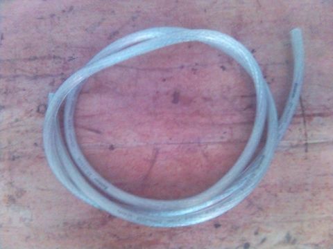 1994 Ford Probe - A length of clear plastic tubing is coiled on a wooden surface. Text is visible on the tubing.