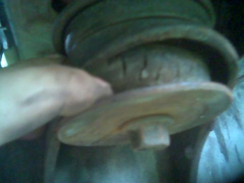 1992 Ford Bronco - Close-up of a rusty suspension component, possibly a bushing, with a hand visible.