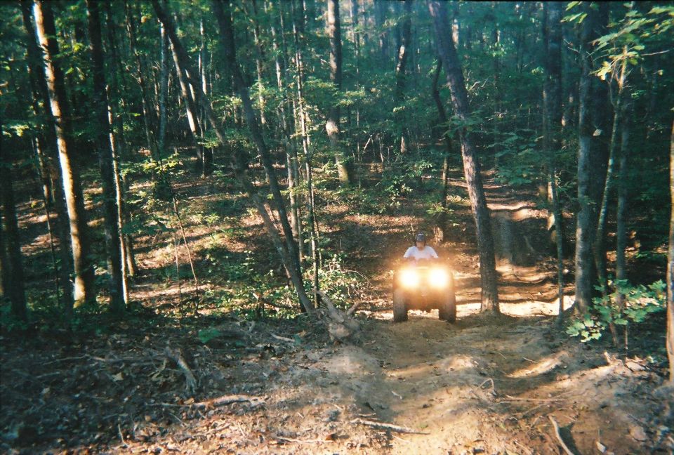 Four-wheeler with bright headlights on a dirt path in a forest