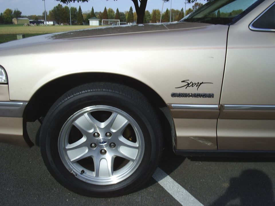 Gold Crown Victoria front fender with Sport badge and silver five-spoke Ford alloy wheel
