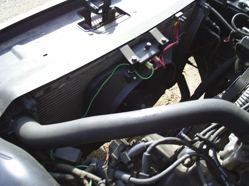Aluminum radiator with bracket-mounted electric fan and wiring in a car engine bay