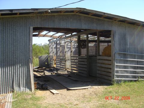 2002 Jeep Wrangler - A rural scene depicts a weathered barn with multiple open stalls and a metal gate, with hay visible within.