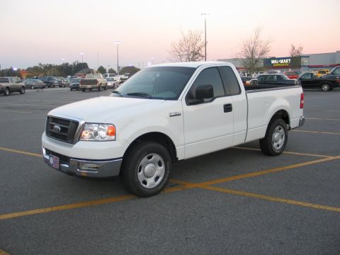 2004 Ford F-150 - A white 2004 Ford F-150 pickup truck is parked in a lot with other vehicles in the background.