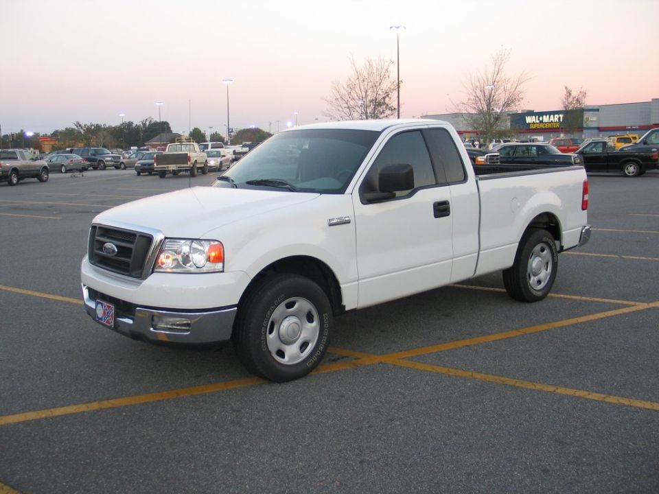 White Ford F-150 regular cab pickup parked in a Walmart parking lot, front three-quarter view