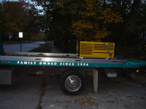 1992 Ford Bronco - A tow truck bed is shown with a yellow toolbox secured on it, the text "FAMILY OWNED SINCE 1956".
