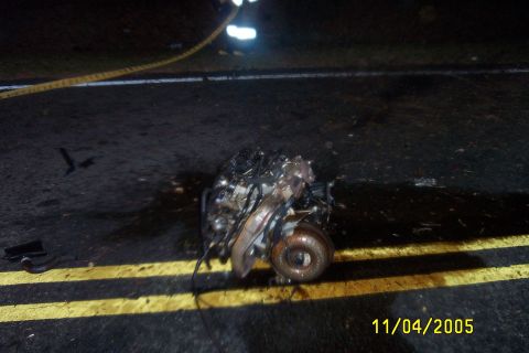 1998 Ford Crown Victoria - Engine and turbocharger assembly on the road, possibly from a vehicle accident.
