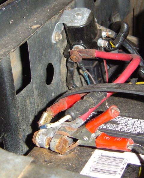 1986 Ford Bronco - Close-up of a starter solenoid mounted to the inner fender of a truck engine bay, with heavily corroded copper terminals and mixed red batt…