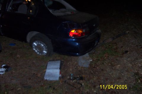 1998 Ford Crown Victoria - The rear of a dark blue sedan is shown, with visible damage to the taillight and bumper area.