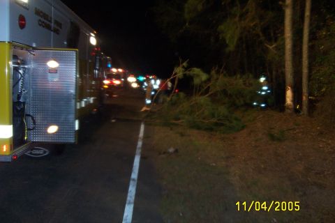 1998 Ford Crown Victoria - Emergency vehicle responding to an incident on the roadside at night, with debris on the ground.