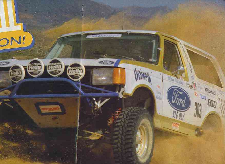 White Ford Bronco off-road race truck numbered 303 racing through desert dust