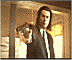 1989 Ford Bronco - Man in a suit and tie aims a firearm directly at the camera.