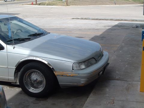 1992 Ford Thunderbird - A silver sedan with distinctive wire wheels is parked on a concrete surface, showing some wear on the front bumper.