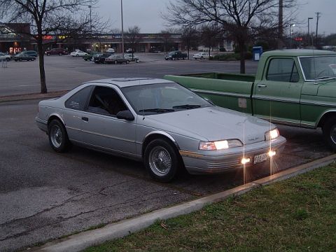 1992 Ford Thunderbird - A 1992 Ford Thunderbird is parked in a lot, with a green pickup truck beside it.