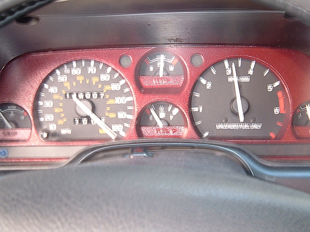 Instrument cluster with red bezel showing speedometer, tach marked Unleaded Fuel Only, fuel and temp gauges