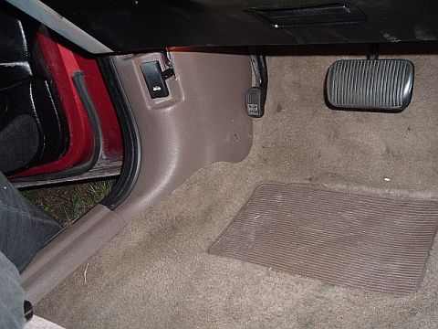 1994 Ford Thunderbird - The driver's side footwell of a car, showing the brake and gas pedals, and the hood release lever.