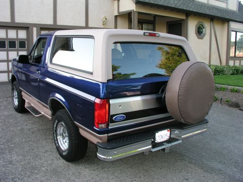 1996 Ford Bronco - This blue Ford Bronco is parked in front of a house with a garage and lawn.
