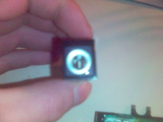 Part with illuminated symbol, held by a hand