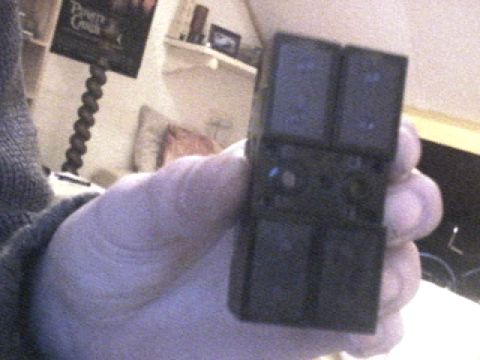 1994 Ford Probe - A hand holds a black window switch assembly with four buttons, likely a replacement part.