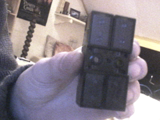 hand holding a black window switch assembly with four buttons