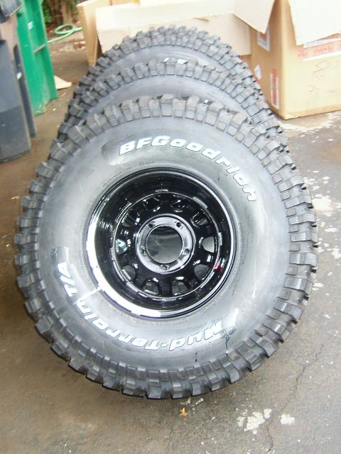 1996 Ford Bronco - Four BFGoodrich Mud-Terrain tires mounted on black rims are stacked and ready for installation.