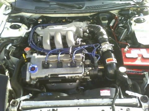 1996 Ford Probe - The engine bay of a 1996 Ford Probe shows its V6 engine and various components.