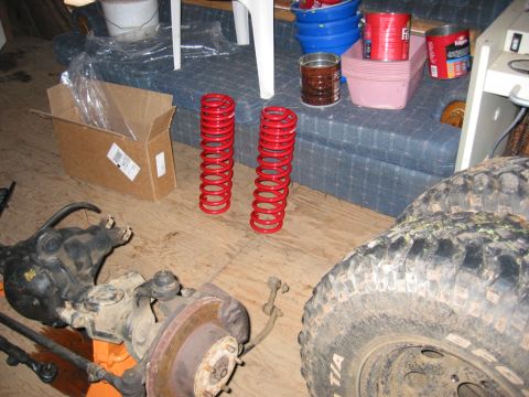 1991 Ford Explorer - Vehicle suspension parts including coil springs, axle, and tire are laid out on a floor.