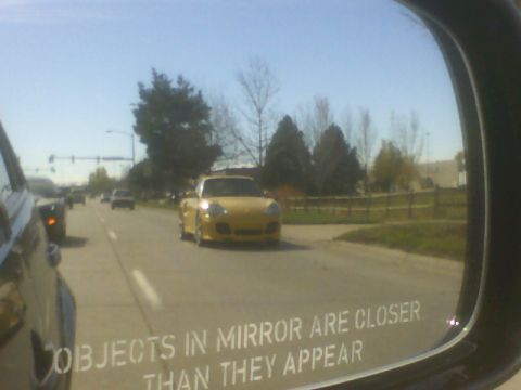1996 Ford Probe - A yellow convertible sports car is seen driving on the road, reflected in a side mirror.
