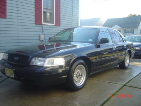 1999 Ford Crown Victoria - This black 1998 Ford Crown Victoria is parked in a driveway, with another vehicle visible in the background.