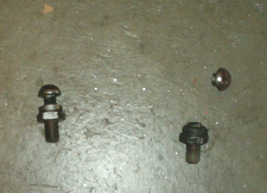 three bolts and nuts on a concrete surface