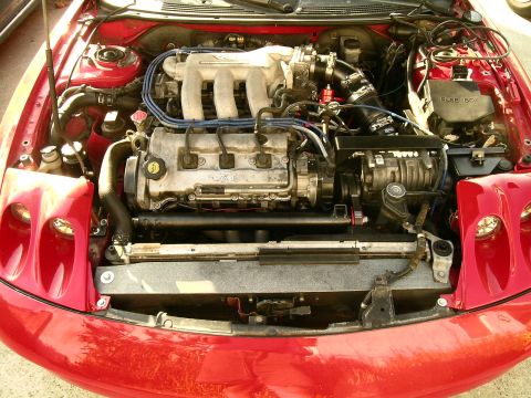 1993 Ford Probe - The engine bay of a red 1993 Ford Probe, its V6 engine and a supercharger.
