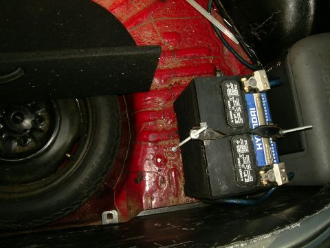 1993 Ford Probe - Spare tire and dual Hyundai batteries installed in the trunk of a car.