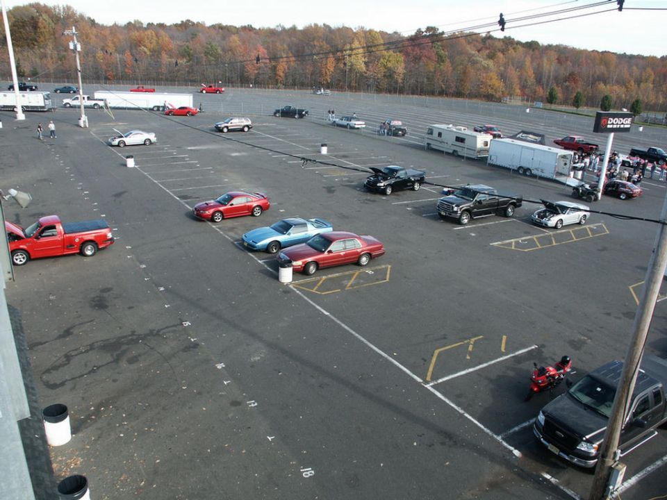 Parking lot with a red pickup, a black pickup, a blue coupe, and a red sedan