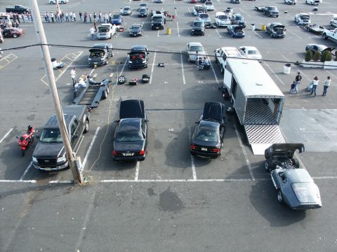 2001 Mercury Grand Marquis - A parking lot scene with multiple vehicles, including two sedans with open hoods and a large trailer.