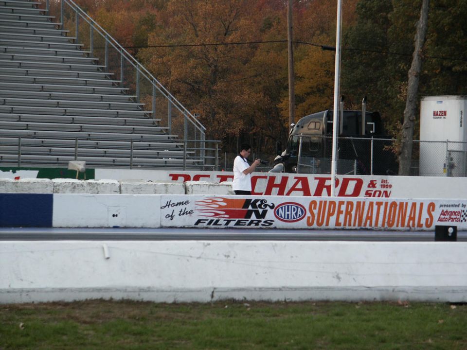 Black truck with a trailer, seen from the front at a drag strip